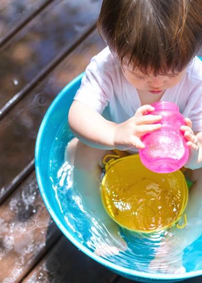 Toddler in a kiddie pool drinking out of a pink sippy cup